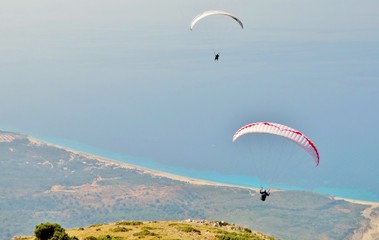 Fotografía panorámica de personas practicando parapente con vista aérea y de fondo el mar azul y...