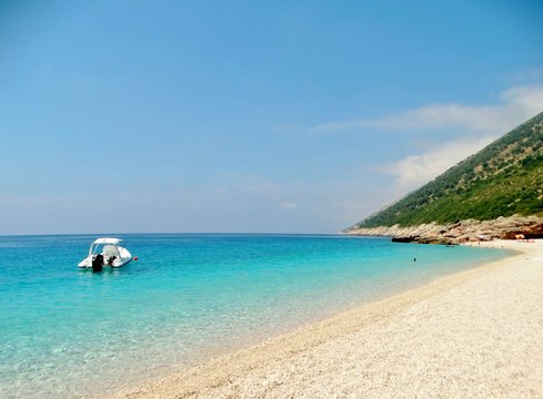 Imagen de una solitaria lancha sobre las aguas transparentes y serenas color turquesa de la playa de Plazhi i Palas&euml;s en la costa abrupta y  preciosa de la rivera albanesa, Mar J&oacute;nico, Albania, Europa