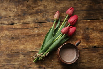 tulips on a wooden table with a cup of cocoa
