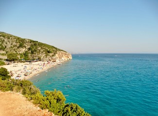 Fototapeta na wymiar Fotografía de la pintoresca playa de arena blanca y brillante de Gjipe en el Mar Jónico, Albania, escondida entre las empinadas laderas de las montañas y bordeada por el agua clara y color turquesa