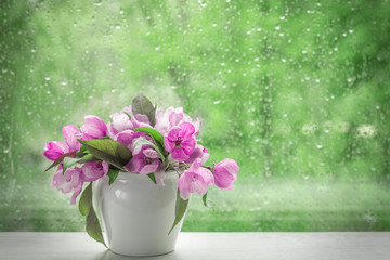 Pink flowers of decorative apple tree in a small white vase on a windowsill. Image for design postcards, calendar, book cover.