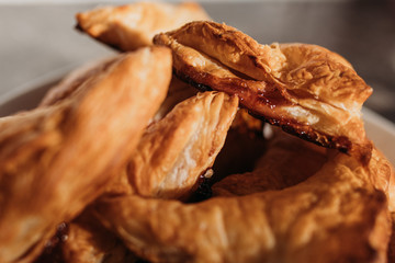 home made puff pastry buns. Triangular in shape with caramelized sugar. On a white plate. Close