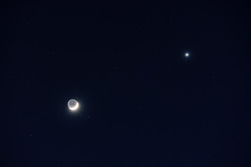 Fototapeta na wymiar la lune est proche de vénus qui brille comme un diamant dans un ciel étoilé bleu noir limpide