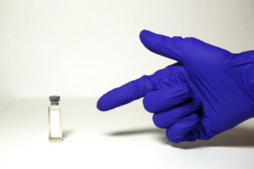 The doctor's hands in blue medical rubber gloves hold a bottle with space for text. Medical concept, the vial with the cure to the epidemic. White background