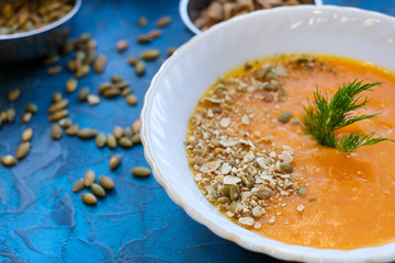Tasty and delicious squash pumpkin soup with toasts, melted cheese, decorated with dill and pumpkin seeds.