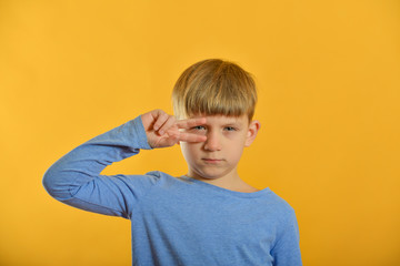 A boy in a blue T-shirt and on an orange background posing.