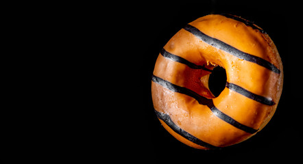 orange donut with chocolate on a black background