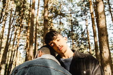 Hugging gay couple in love at the forest