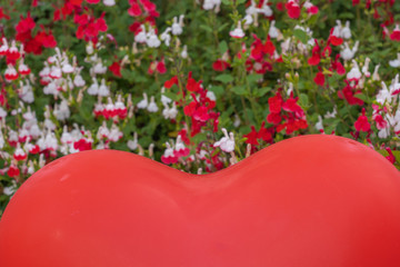 Gennevilliers, France - 05 08 2020: Heart shaped red balloon surrounded by red and white flowers...