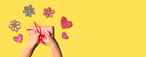Little boy making a gift box with flowers and hearts drawings overhead view