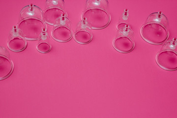 Jars for hijama. Vacuum pumps on a pink background