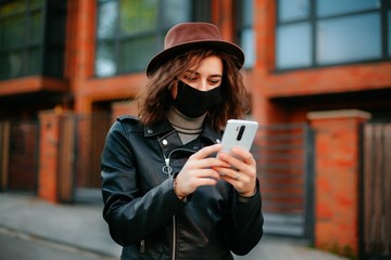 young woman with mobile phone in the city in mask. coronavirus. covid-19. 