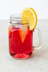 Jar of fresh strawberry lemonade with fruit slices. Refreshing drink