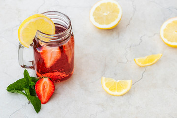Summer background with drink in jar on marble table. Strawberry lemonade and fruit slices and mint. Space for text