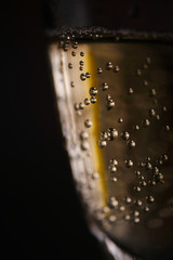 Naklejka na ściany i meble Champagne bubbles in a glass on a dark background