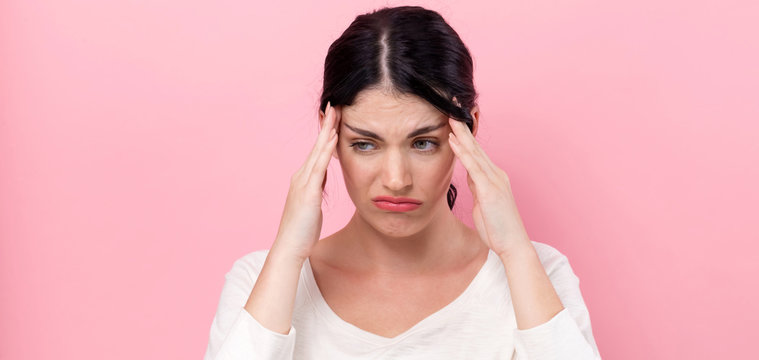 Young woman feeling stressed on a pink background