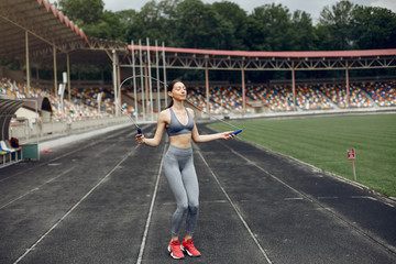 Beautiful girl at the stadium. Sports girl in a sportswear. Lady with jump rope