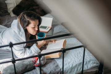 A woman is lying on a bed with a book