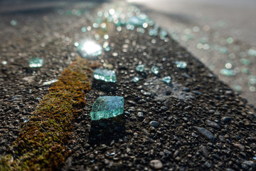 broken glass pieces scattered on the road side under the sun