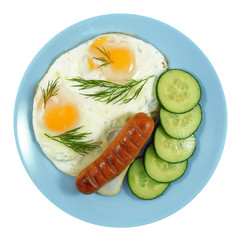 Breakfast of crambled eggs with fried sausage, fresh sliced cucumber and dill on blue plate isolated on white background, top view.