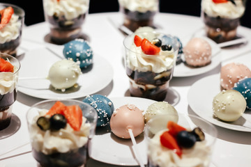 Desserts with whipped cream and strawberries on a white table. Glamorous style