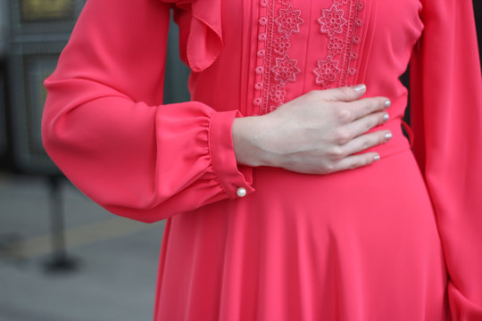 The girl put her hand on her waist. In a beautiful rose-orange dress. Glare plan. Dress for nikaha