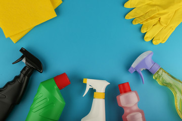 flat lay with spray bottle detergent or sanitizer, cleaning cloth and gloves on blue background with copy space. cleaning products view from above