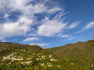panoramic view of the Apuan Alps between the green mountains and the blue sea between the lush hills
