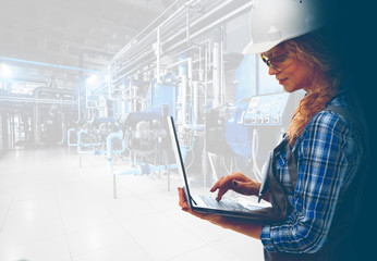  Attractive female industrial engineer with laptop inspect modern industrial gas boiler room. Heating gas boilers, pipelines, valves. Mixed media with copy space