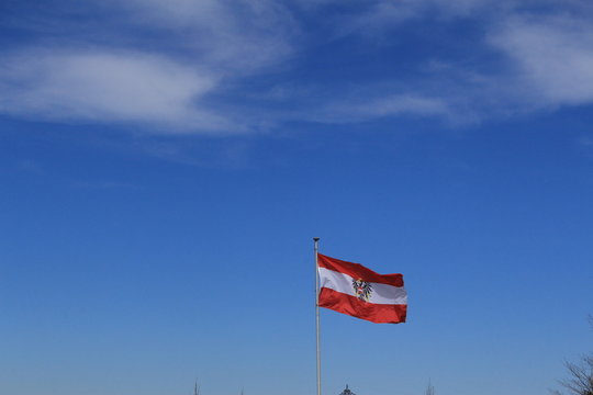 Austrian national flag is waving in the wind against blue sky background