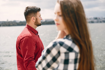 Obraz premium Cute couple in a park near river. Lady in a chirt. Guy in a red shirt