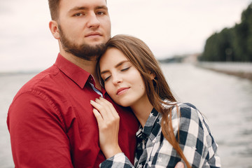 Obraz premium Cute couple in a park near river. Lady in a chirt. Guy in a red shirt