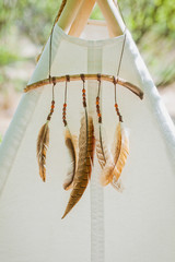 a white children's wigwam decorated with feathers © Anna
