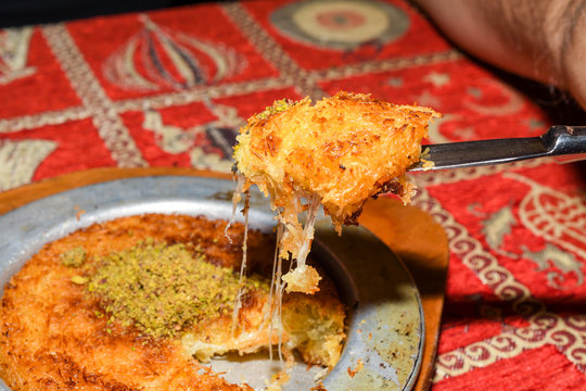Turkish dessert kunefe with pistachio powder. Kunafa, kadayif with pistachio powder and cheese hot
