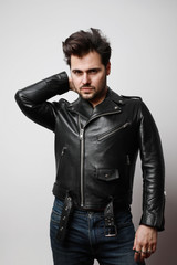 Vertical portrait of modern stylish young hipster man in a leather stylish jacket posing over a white background. 