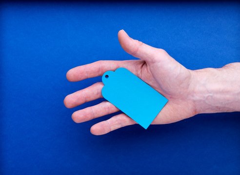 Main tenant une étiquette bleu à personnaliser sur fond bleu
