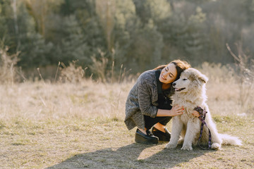 Woman in a spring forest. Girl with cute dog. Brunette in a gray jacket.