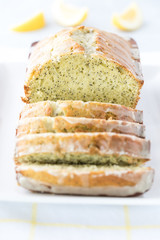 A front facing close up view of a lemon poppy seed loaf that has been sliced into.