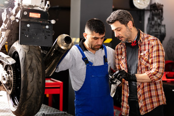 Motorbike repairman working in repair shop.