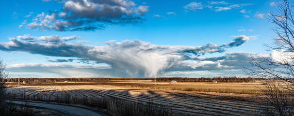 Beautiful extra wide and large slow tornado panorama over scandinavian forest and field, sunny day with very heavy dark clouds , wooden poles for power supply, wooden unpainted aged sheds
