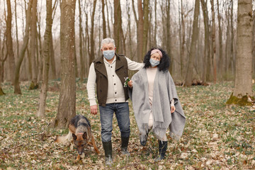 Seniors in a forest. People walks in a masks. Family with dog. Corona virus theme.