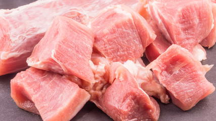 Raw fresh pieces of pork for roast on a dark slate board close-up