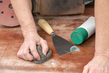 El carpintero repara un defecto en la madera con masilla de relleno