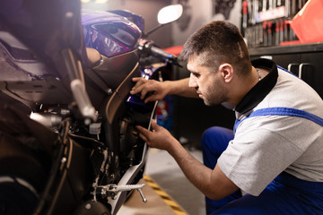 Motorbike repairman working in repair shop.