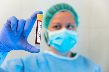 Doctora con protección, máscara y gorro, mostrando un test positivo de sangre del virus llamado...
