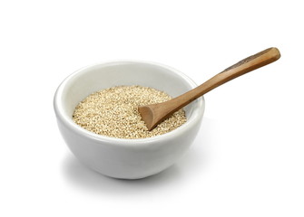 Organic Quinoa (Chenopodium quinoa) seeds in a white bowl with wooden spoon isolated on white background. Macro close up. Top view. quinoa seeds isolated on white background.
