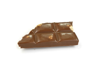 A broken piece of chocolate with hazelnuts isolated on white background. Milk chocolate tiles with nuts isolated on white.