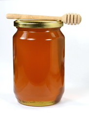 Jar with organic honey isolated on white. Glass jar full of honey and dipper isolated on white background.