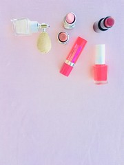Lots of make up items with pink background, lipsticks and nail  polish