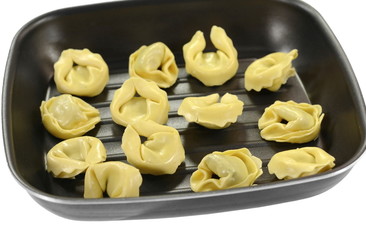 Italian traditional tortellini pasta or ravioli stuffed with spinach in the pan, isolated.
